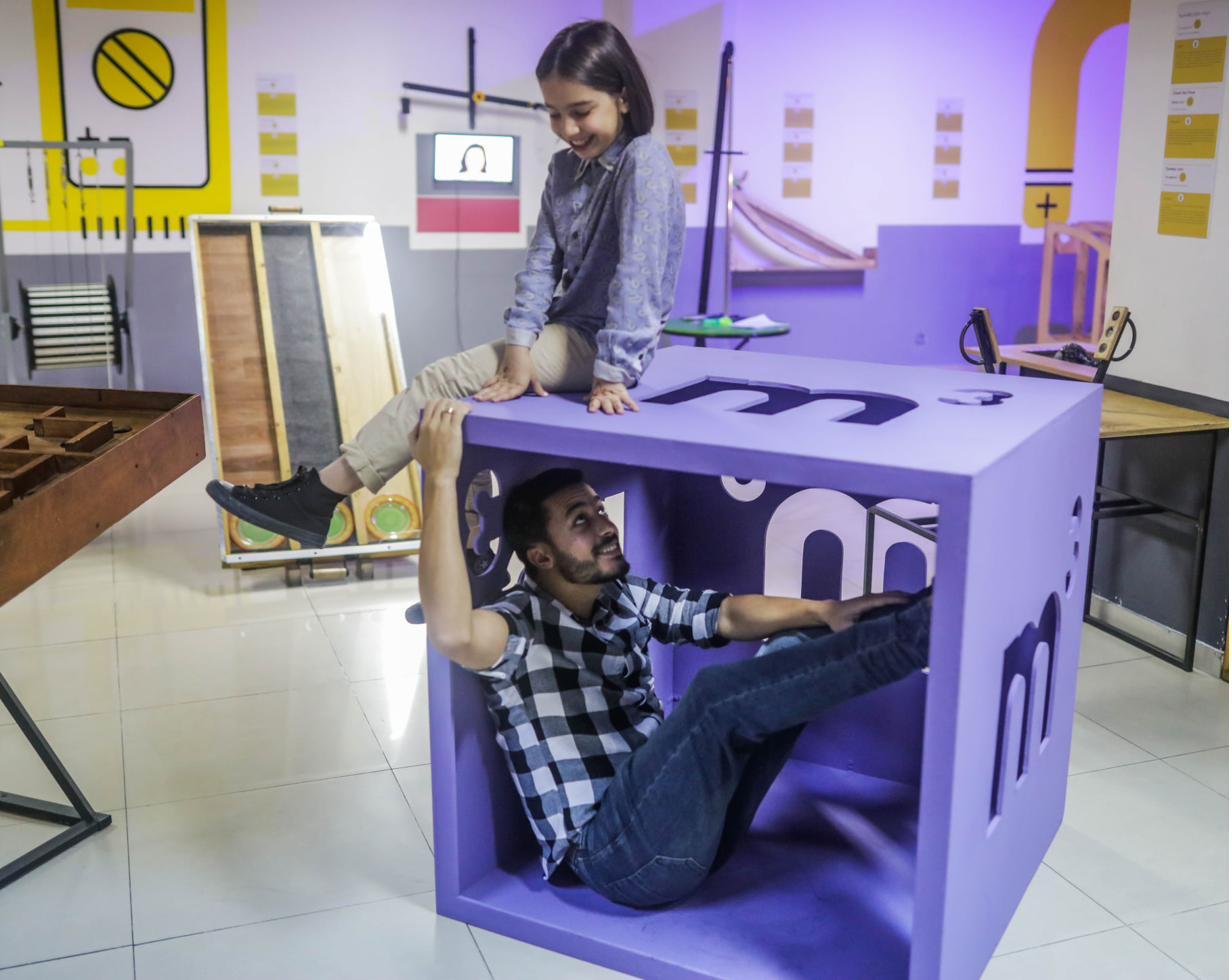 Inside Experimentorium: a child and a guide interacting with one of the museum's exhibits.